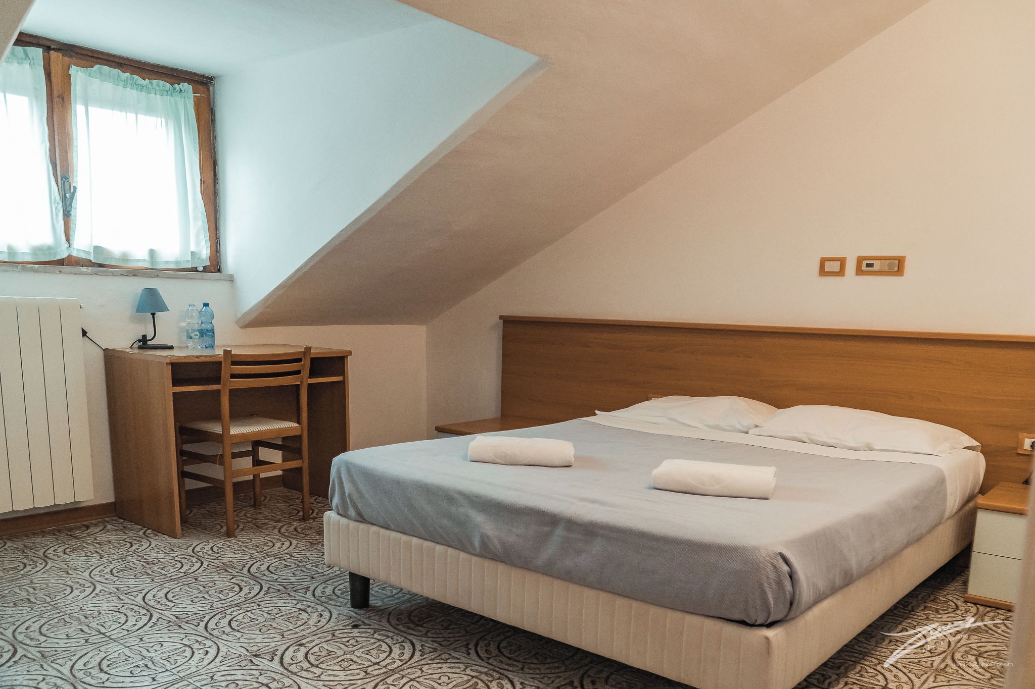 A bedroom with a bed, a desk, and a chair.