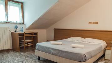 A bedroom with a bed, a desk, and a chair.