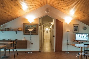 A hotel interior with a wooden ceiling, a reception desk, a dining area, and a hallway leading to the bedrooms. - Tramonti Green (Tramonti)