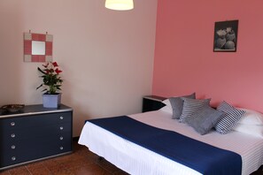 A bedroom with a bed, a dresser, a potted plant, a mirror, and a wall art piece. - Tramonti Green (Tramonti)