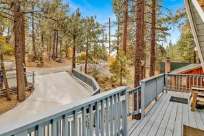 A wooden deck with a railing, surrounded by tall pine trees. - Sweet Cabin Home Gateway #2576 (Big Bear City)