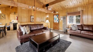 Ein Holzinterieur mit zwei Ledersofas, einem Couchtisch und einem Essbereich.