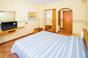 A bedroom with a bed, a TV on a stand, a mirror, and a door leading to another room. - Hotel San Pietro Beach - Letojanni (Letojanni)