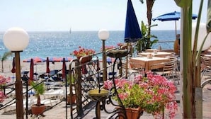 A seaside restaurant with outdoor seating, a view of the ocean, and potted plants. - Hotel San Pietro Beach - Letojanni (Letojanni)