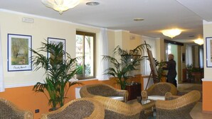 A lobby with wicker furniture, large potted plants, and artwork on the walls.