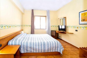 A hotel room with a bed, a TV, a desk, and a window with curtains. - Hotel San Pietro Beach - Letojanni (Letojanni)