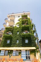 Un edificio con varios balcones, un restaurante llamado 'S. Pietro Ristorante' con terraza, y un letrero que dice 'PIZZERIA - BAR'.