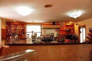 A kitchen with wooden cabinets, a countertop with various items, a window, and a clock on the wall. - Hotel San Pietro Beach - Letojanni (Letojanni)