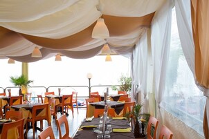 Un comedor interior con mesas y sillas, una barandilla y vistas por una ventana.