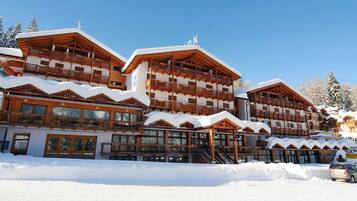 Un lodge in legno a più piani con balconi e ampie finestre, circondato dalla neve.