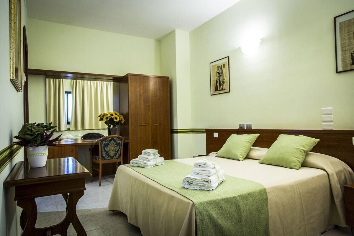 Une chambre d’hôtel comprenant un lit, un bureau, une chaise, une armoire et une salle de bain.