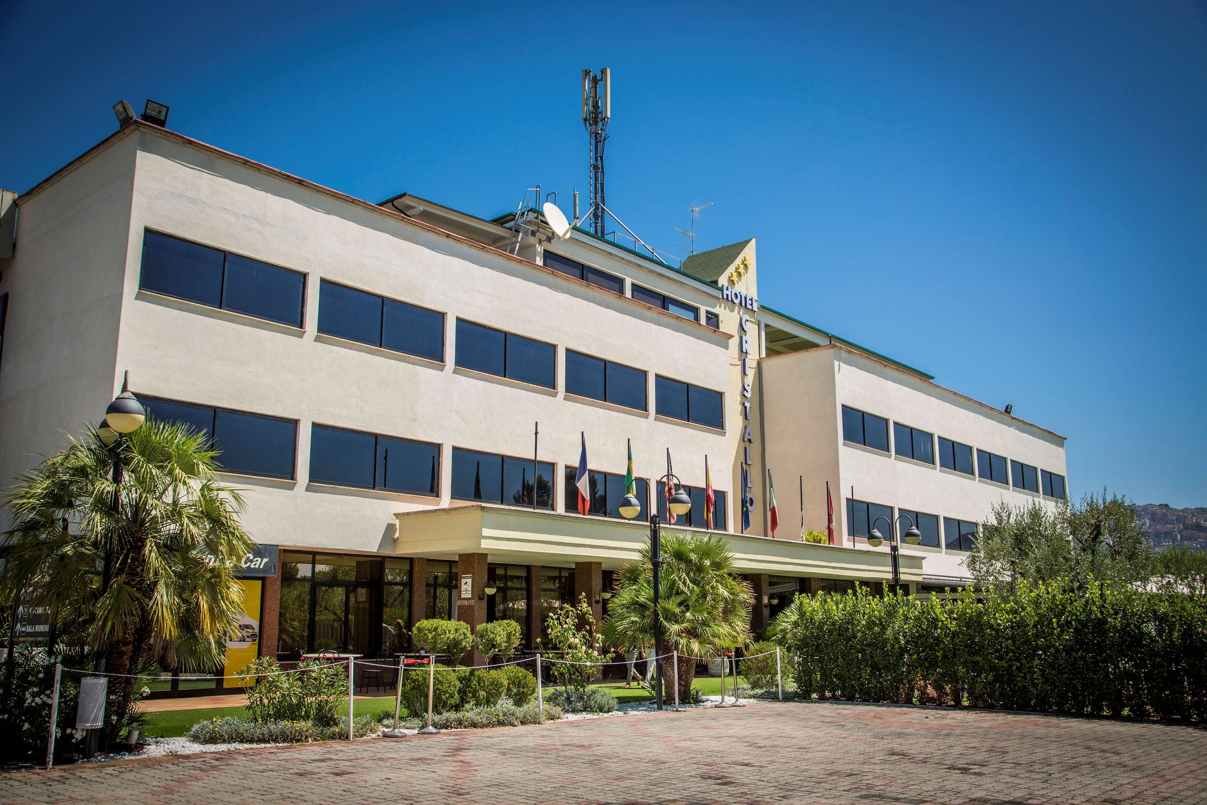 A modern hotel with a flat roof, multiple windows, and flags.