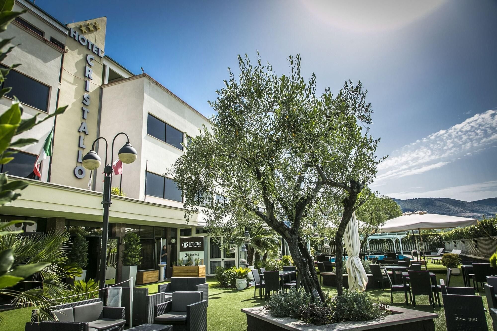 A hotel with outdoor seating and a large tree in the center.