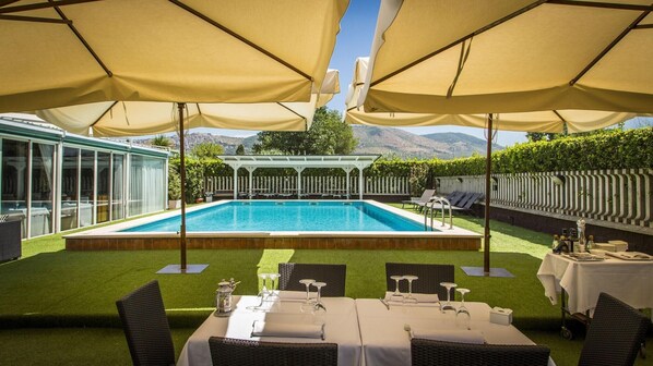 Et poolområde med pool, udendørs møbler og en pergola.