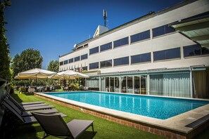 Een hotel met een zwembad, terras en een vlag op het gebouw.