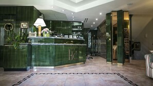 Un espace d’accueil avec un comptoir en marbre vert, une horloge et un bureau de réception.