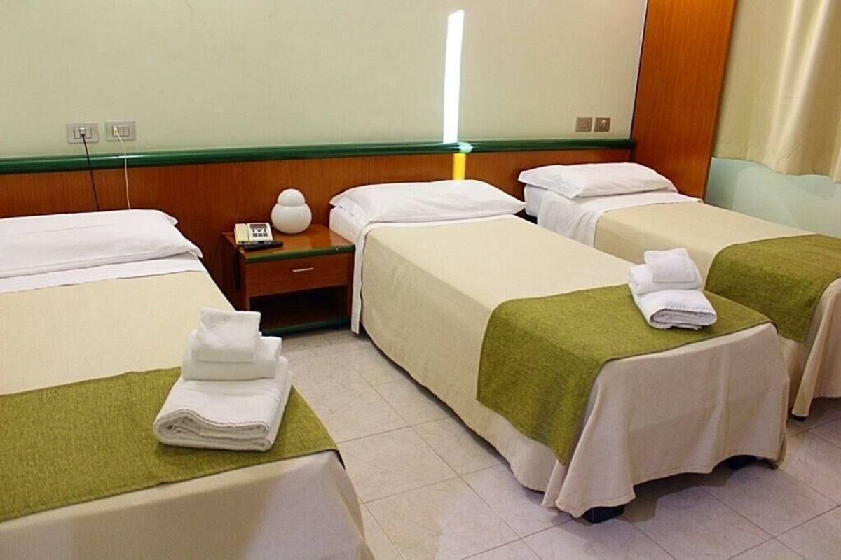 Une chambre d’hôtel avec deux lits simples, une table de chevet avec une lampe et une petite table avec un téléphone.