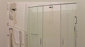 Kylpyhuoneessa on lasiseinällä varustettu suihku, kaksi pesuallasta, wc ja roskakori.