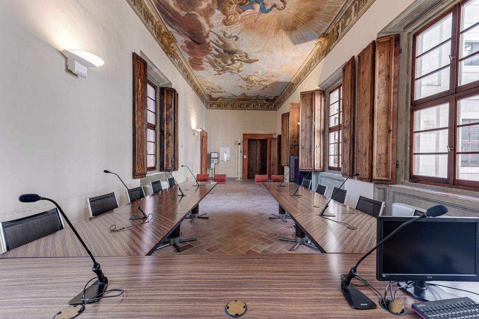Une salle de conférence équipée d’une longue table, de nombreuses chaises, de microphones et d’ordinateurs.