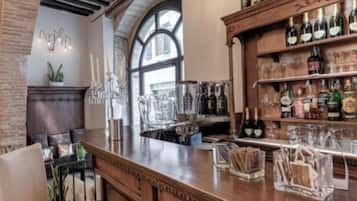 A bar area with a wooden counter, bar stools, and shelves of bottles and glasses.