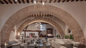 Um interior acolhedor e rústico, com tetos de tijolos em arco, assentos confortáveis e uma atmosfera agradável.
