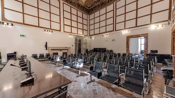 A conference room with a long table, rows of chairs, a fireplace, and a stone-tiled floor.