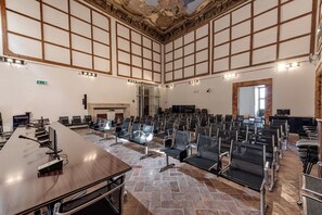 A conference room with a long table, rows of chairs, a fireplace, and a stone-tiled floor. - B&B Borgo Medievale San Quirico D'orcia (San Quirico d'Orcia)