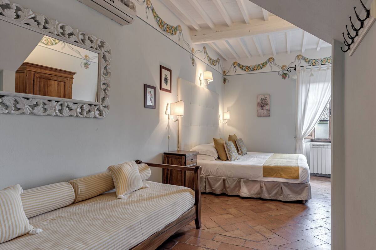 Una camera da letto con un letto, un divano, un comodino e uno specchio.