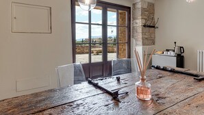 A rustic dining table with chairs, a clear glass vase with reed sticks, and hanging pendant lights. - B&B Borgo Medievale San Quirico D'orcia (San Quirico d'Orcia)