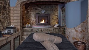 A spa room with a stone fireplace, a massage table, and a stone wall. - B&B Borgo Medievale San Quirico D'orcia (San Quirico d'Orcia)