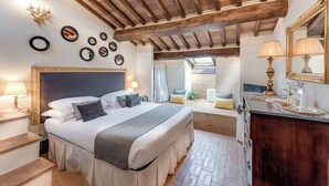 Um quarto com uma cama grande, teto de madeira, escrivaninha com abajur e espelho.