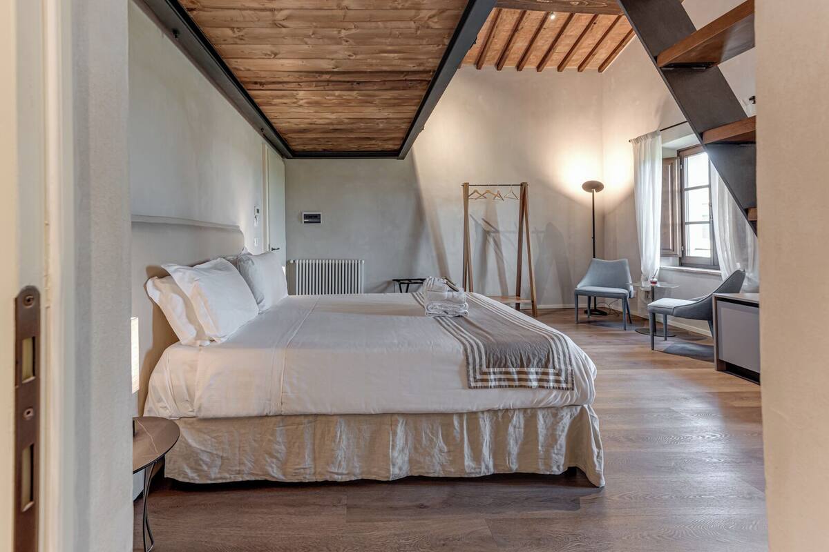 Una camera da letto con un letto grande, un termosifone, una sedia, una scrivania e una finestra.