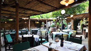 An outdoor restaurant with tables and chairs, covered by a wooden roof, and surrounded by greenery. - B&B Borgo Medievale San Quirico D'orcia (San Quirico d'Orcia)