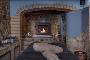 Una stanza spa con un camino in pietra, un lettino per massaggi e una parete in pietra.
