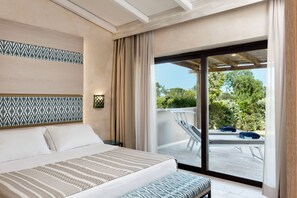 A bedroom with a bed, a nightstand, a patterned headboard, and a view of an outdoor deck. - Baglioni Resort Sardinia (San Teodoro)