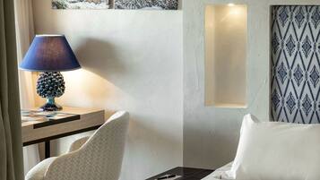 Una habitación de hotel con escritorio, silla, cama, lámpara y papel tapiz estampado.