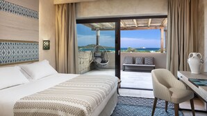 Habitación de hotel con cama, escritorio, silla, sillón colgante y vista al mar.