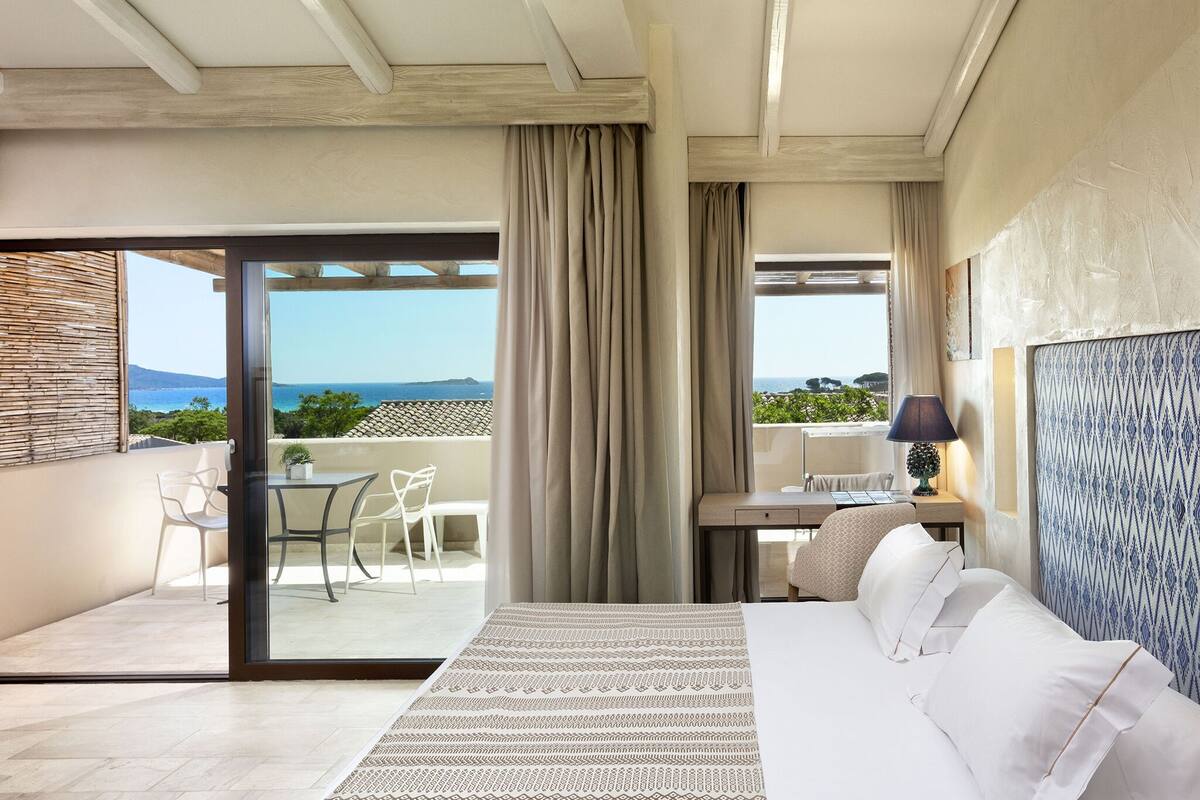 Une chambre avec un lit, un bureau et une vue sur la mer.