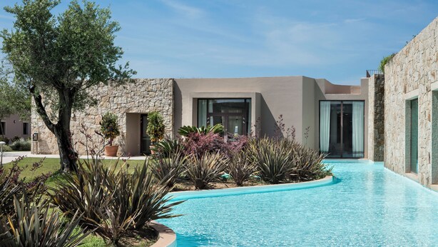 Un espace piscine moderne avec un mur en pierre et une entrée avec une porte en verre.