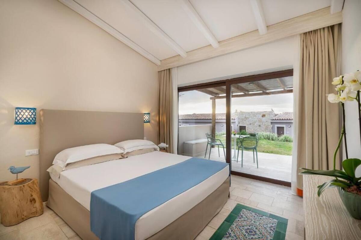 Une chambre avec un lit, une vue sur l’extérieur et un balcon équipé de chaises.