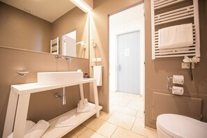 Un baño moderno con un lavamanos blanco, espejo, toallero y retrete.