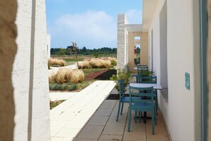 Un pasillo con vista a un jardín ajardinado y un comedor con sillas y mesas azules.