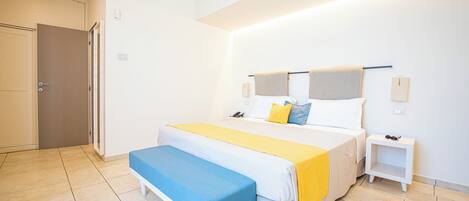Une chambre à coucher avec un lit, des tables de chevet, un banc et une porte.