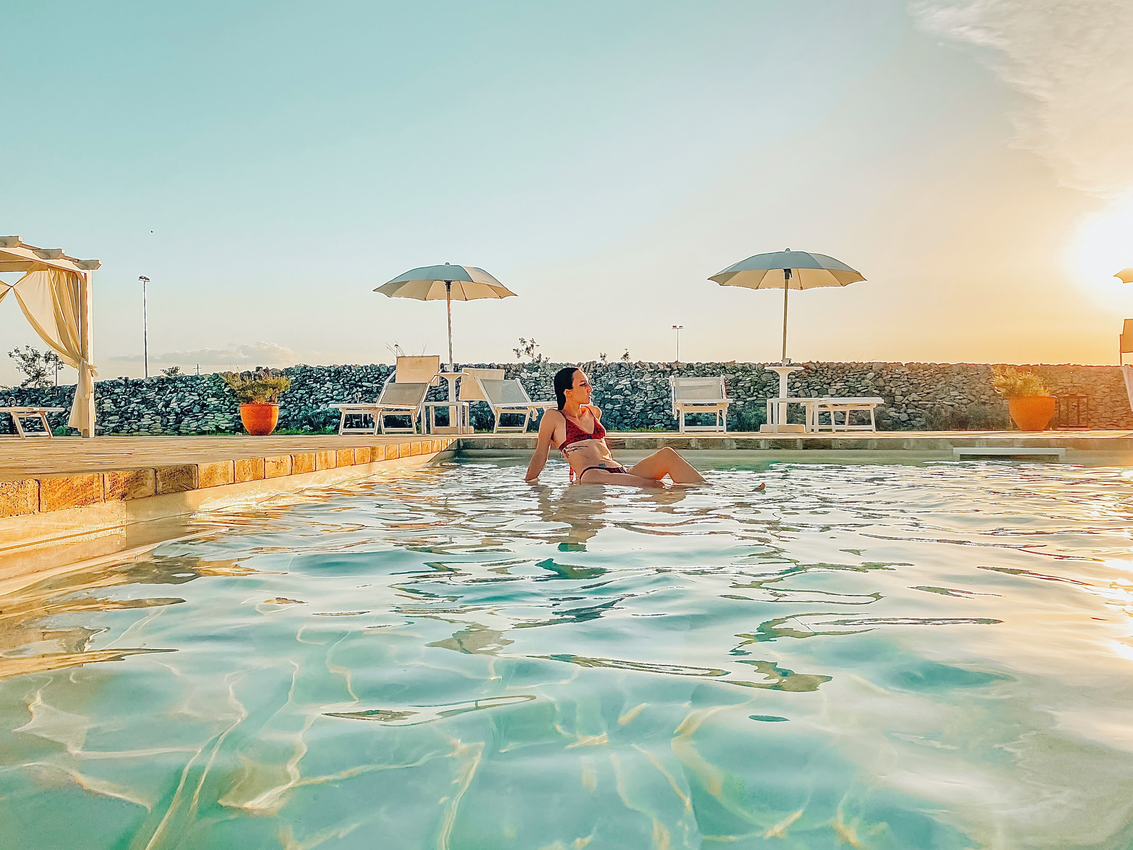 Un espace piscine avec une eau claire, des chaises longues et des parasols.