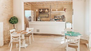 Un comedor moderno con mobiliario blanco y una encimera central con una cafetera.