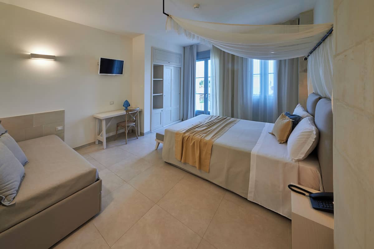 A hotel room with a bed, a desk, a chair, and a TV.