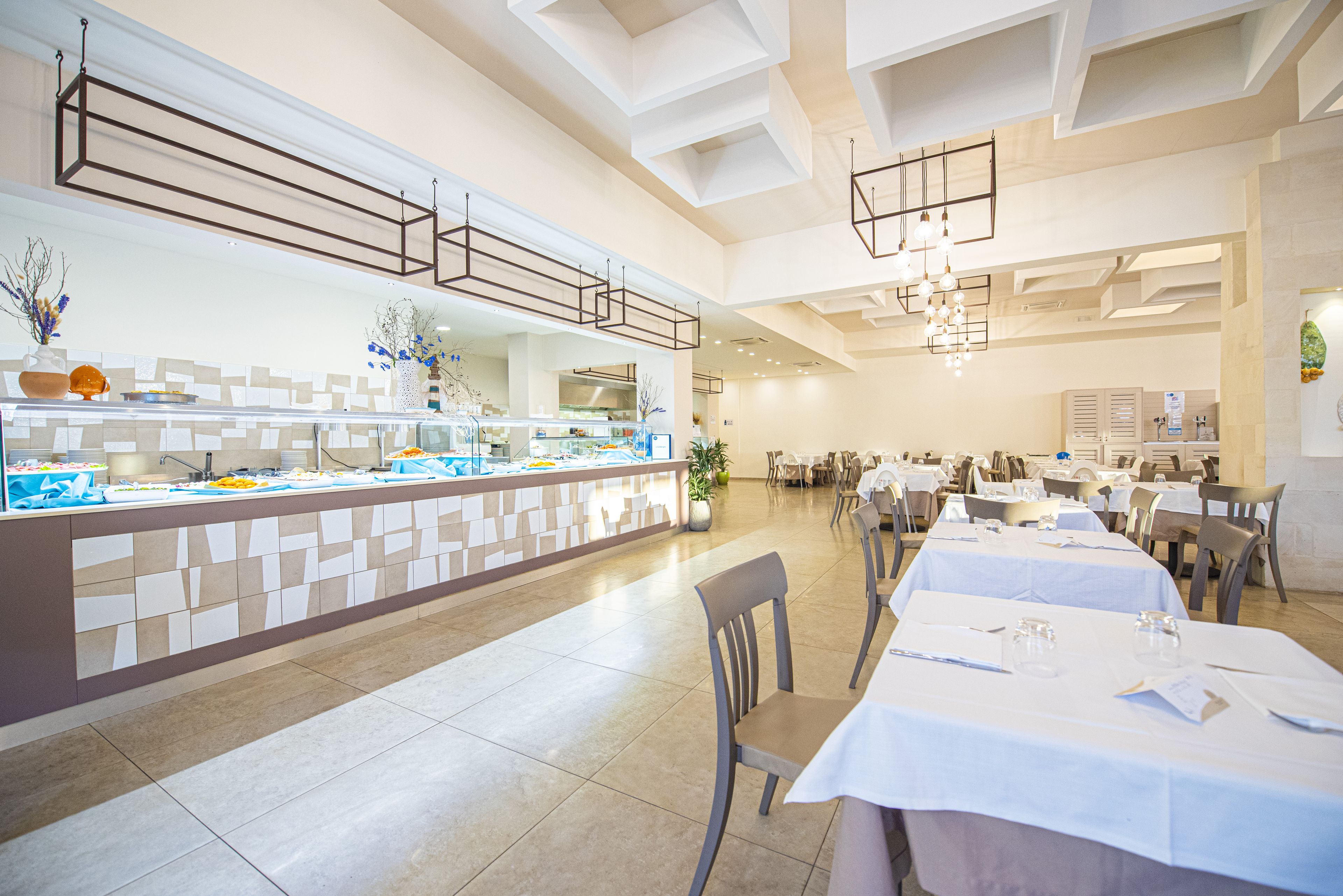 A modern dining area with a buffet counter, multiple tables, and chairs.