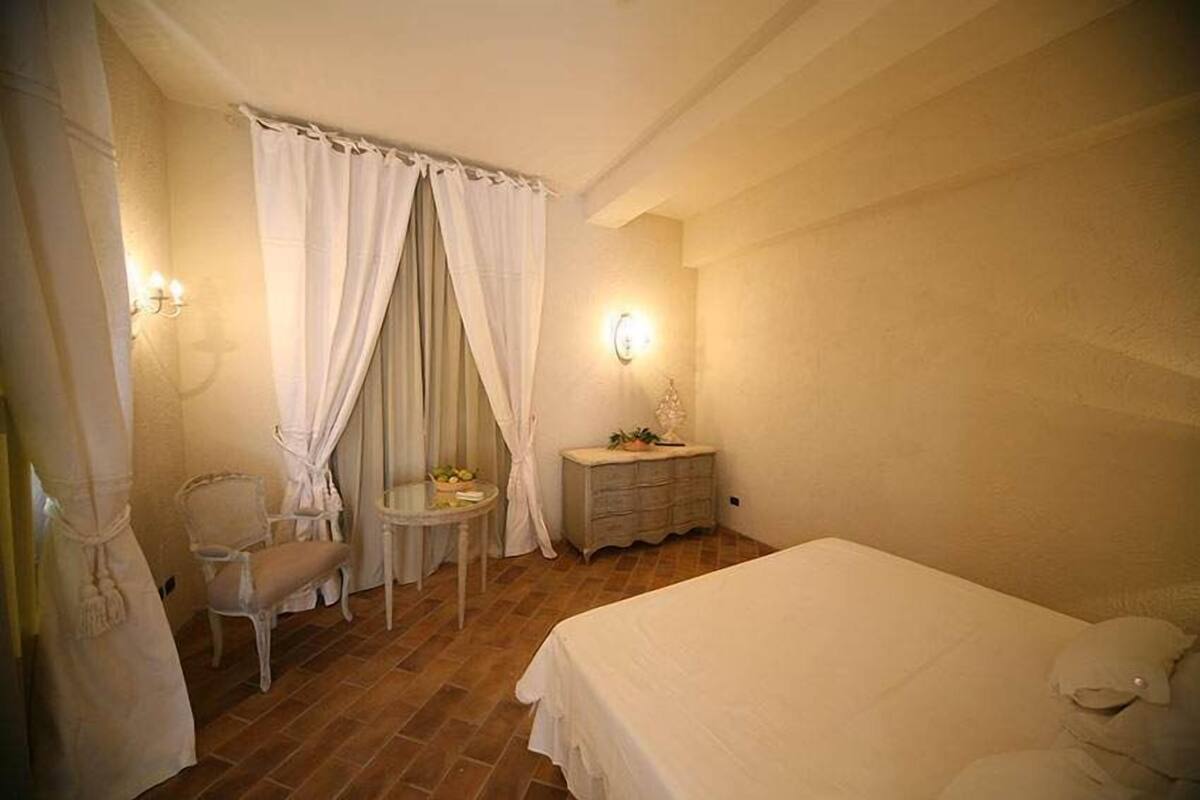 Ein Schlafzimmer mit Bett, Stuhl, einem kleinen Tisch und einem Schminktisch.