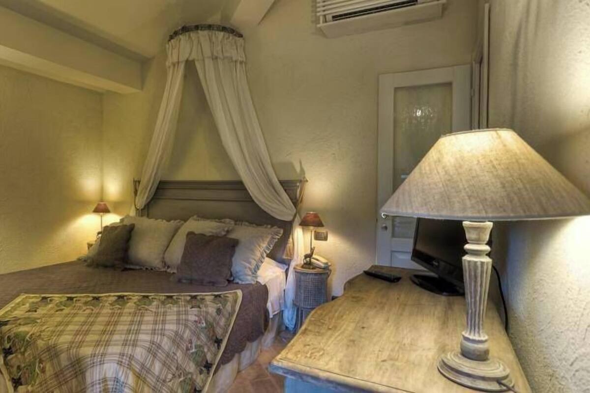 Ein Schlafzimmer mit einem Bett, einem Nachttisch mit Lampe und einem Himmelsbett.