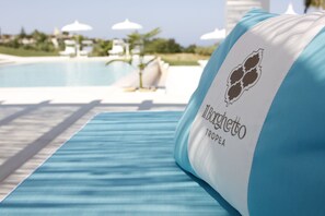 A poolside lounge area with a blue-striped towel and a pillow with 'Il Borghetto TROPICA' branding. - Il Borghetto Creative Resort (Tropea)